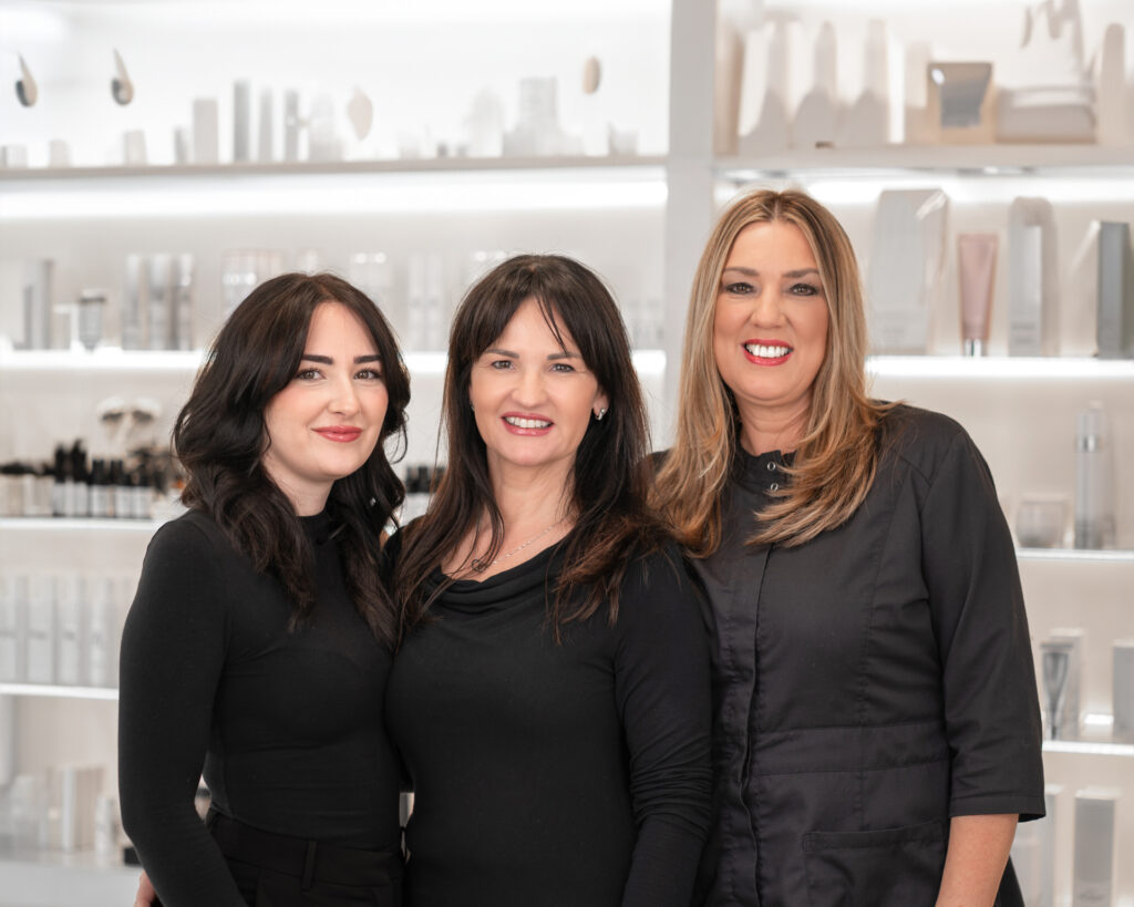 Drei hübsche Frauen vor einem Regal in einem Kosmetikinstitut